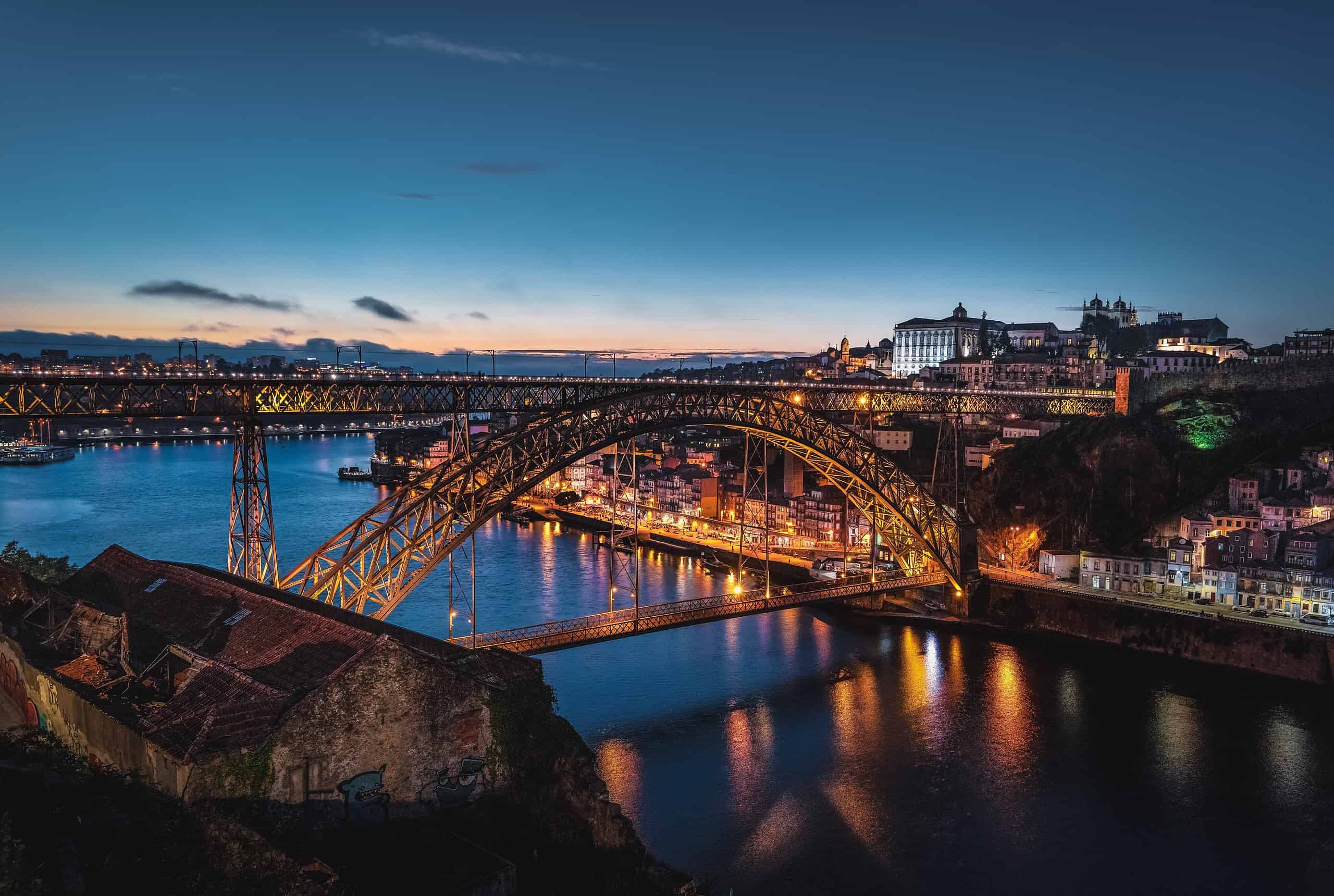 Porto Portugal lit up at night, reflecting off the water.